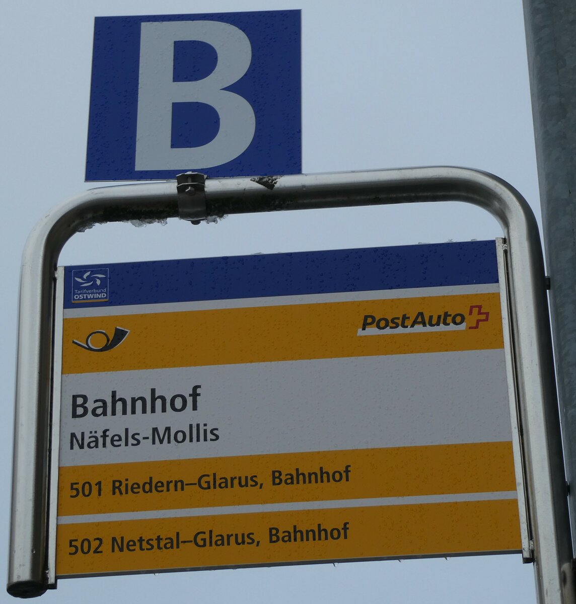 (231'965) - PostAuto-Haltestellenschild - N�fels-Mollis, Bahnhof - am 10. Januar 2022
